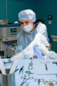 A female surgeon focuses on a procedure, surrounded by surgical tools in a hospital operating room.