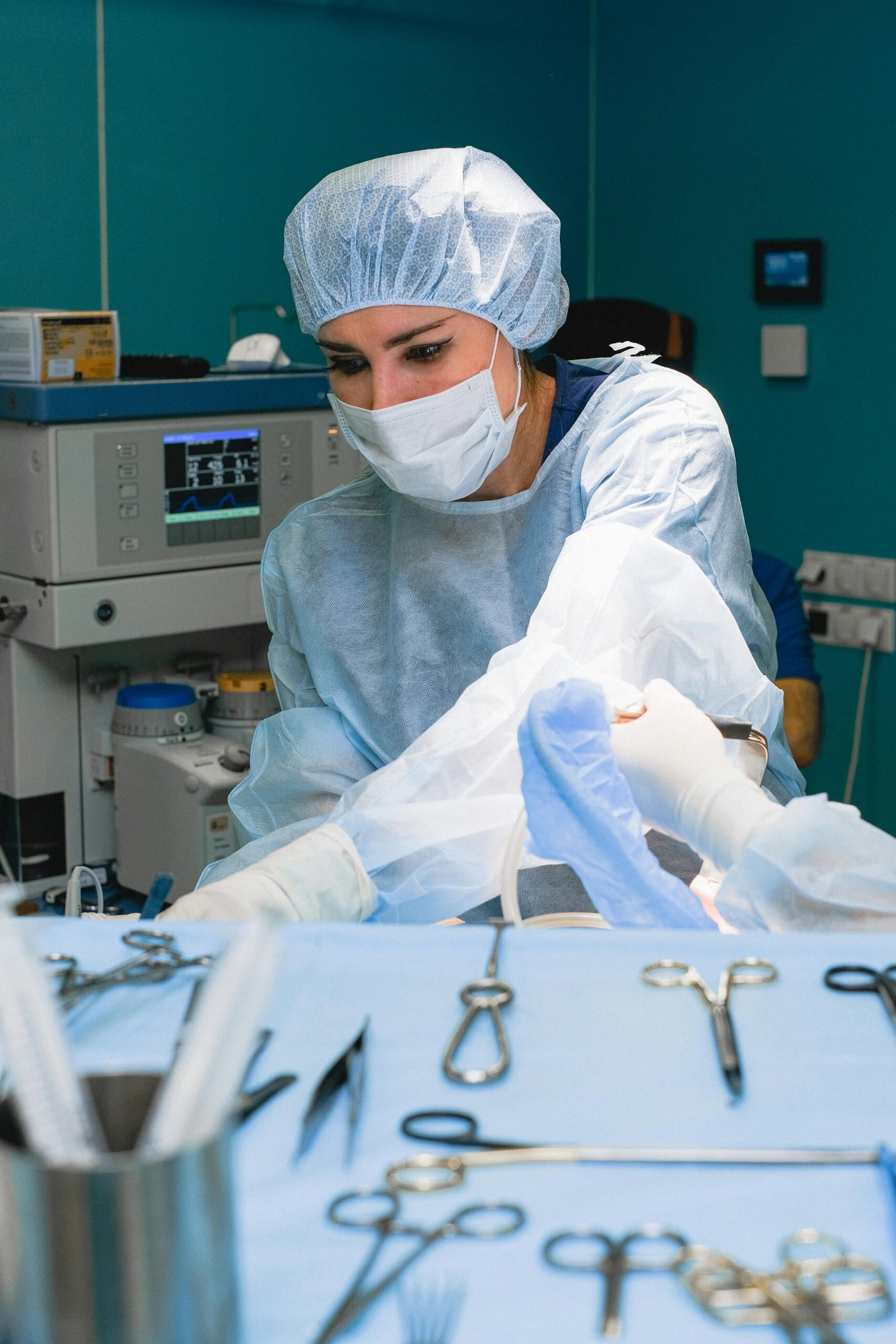 A female surgeon focuses on a procedure, surrounded by surgical tools in a hospital operating room.